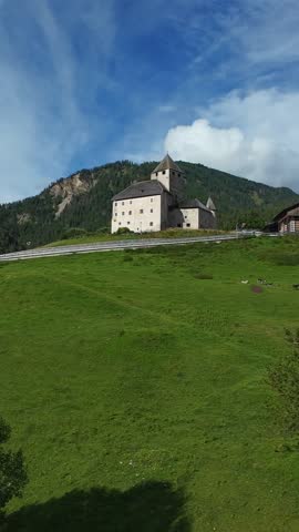 Majestic Hill Fortress, Vast Green Hill With Clouds, Castle Perched On Expansive Grassy Slope Under Dramatic Clouds, Fortified Castle Sits Atop Broad Meadow With Scenic Sky Backdrop