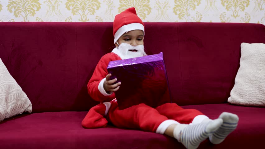 happy child wearing santa outfit with christmas present
