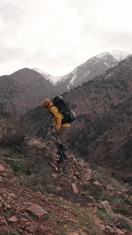 Solo hiker in yellow jacket climbing mountain ridge with powerful endurance showing healthy lifestyle outdoor tourism motivation strength resilience solo adventure alpine morning trekking achieving