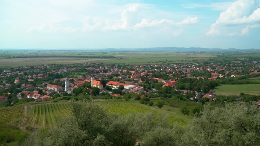Distant view of Tarcal, Hungary, featuring its charming village, Tokaj-hegyalja vineyards, and rolling hills under a clear autumn sky, captures the serene beauty of the Hungarian countryside.