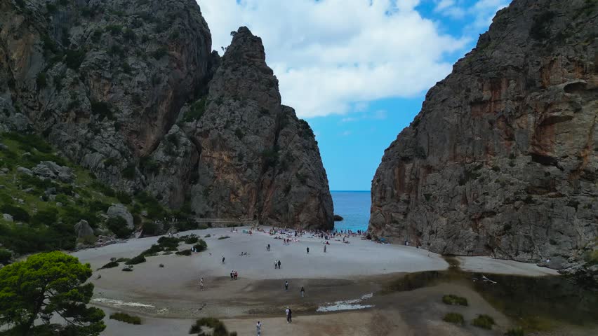The secluded Sa Calobra cove and beach, framed by towering rocky cliffs in the Serra de Tramuntana mountains. The Torrent de Pareis canyon meets the crystal-clear turquoise water here.