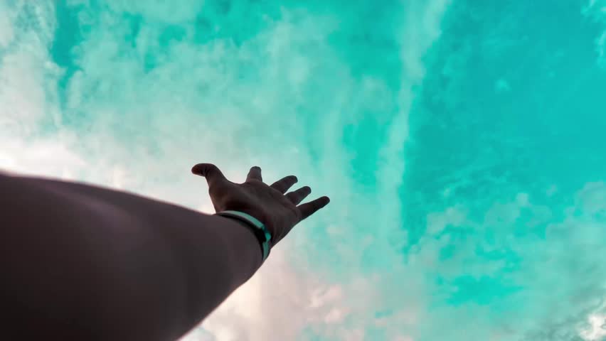 Hand Reaching Toward Dramatic Teal Sunset Sky and Calm Lake Horizon