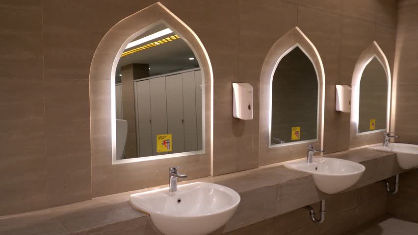Surakarta, Indonesia - June 18, 2025: A modern bathroom with rows of white sinks and Moorish-style curved mirrors creates a clean and elegant impression.