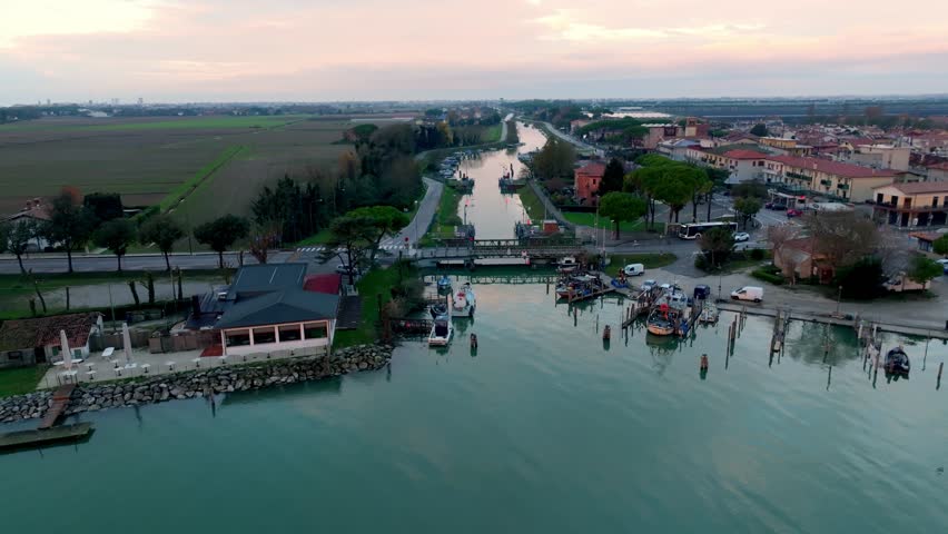 Aerial drone view of Cortellazzo fishing village at sunset near Jesolo, Italy. Scenic estuary where the Piave River meets the Adriatic Sea, featuring the harbor and boats