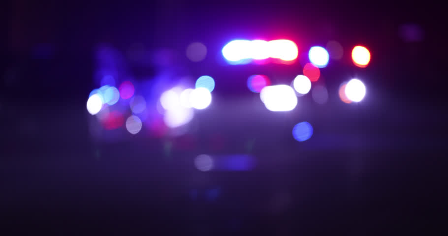 Abstracted de-focused illuminated night view of police units on a city street.