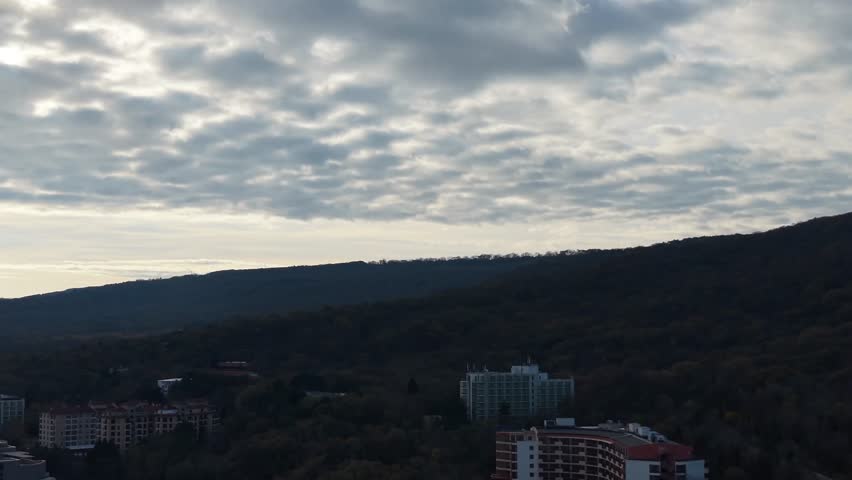 Aerial drone view of dramatic cloudy sky above dark hills, moody atmosphere, layered clouds, natural landscape, cinematic horizon, serene twilight.