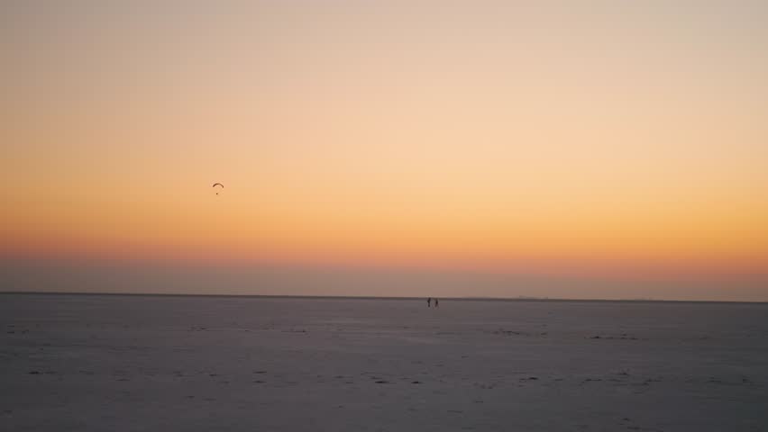 4K Landscape shot of White Rann of Kutch during the sunset as seen from Dhordo in Kutch, Gujarat, India. Scenic view of sunset at the White desert with tourists far away enjoying the scenic views.