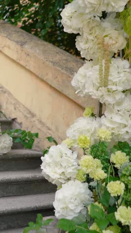 A beautiful wedding arch with white flowers and festive decor in an old Italian courtyard with architectural features. A symbol of romance and love on the bride and groom