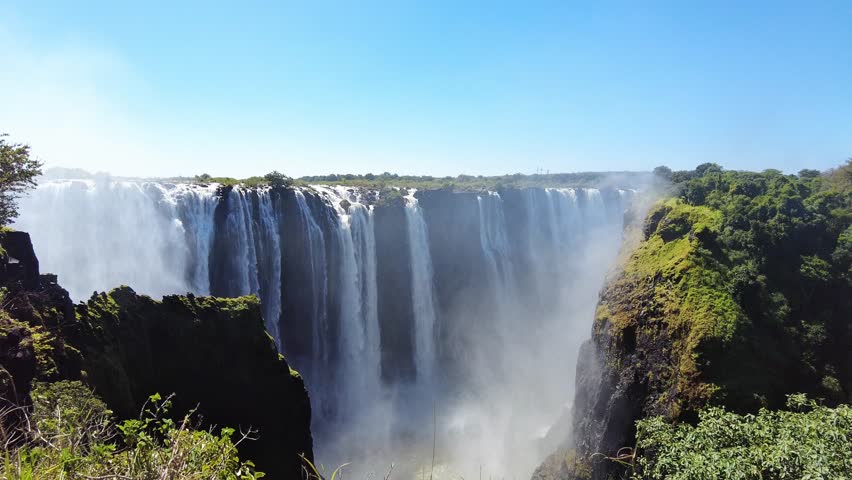 Static shot of Victoria Falls with the Zambezi River plunging over the Main Falls into the narrow gorge, mist rising above rainforest-covered cliffs near the town of Victoria Falls, Zimbabwe, Africa