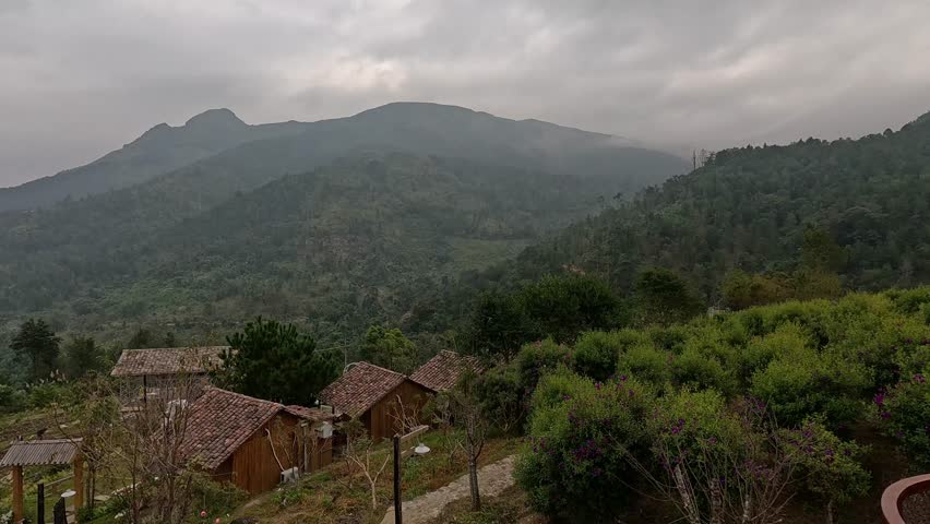 Mountain village landscape in northern Vietnam, featuring traditional wooden houses surrounded by blooming flower gardens and lush greenery