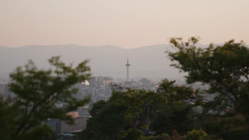 Sunset view of Kyoto tower through trees in Kyoto, Japan.