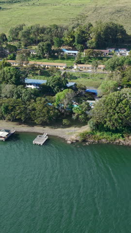 Drone aerial footage of Lago Calima, Valle del Cauca, showcasing lush greenery and serene water. Captured in vibrant daylight, this vertical video is perfect for social media and mobile viewing.