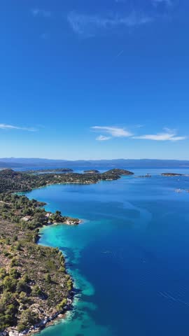 Aerial drone view of Diaporos Island seen from Fteroti Beach with sandbanks, shallow lagoon and turquoise water in Sithonia, Chalkidiki, Greece. Coastal Mediterranean landscape.
