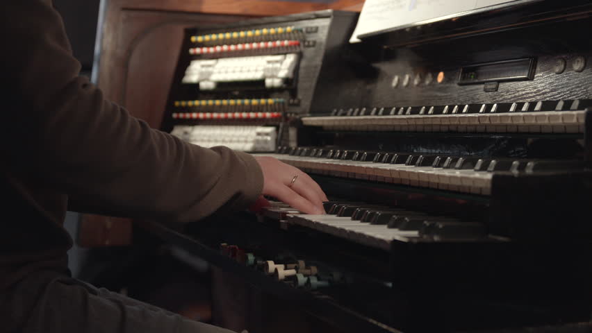 Closeup Of Musician Practicing Hymn Arrangements And Adjusting Instrument Settings In Quiet Chapel. Media