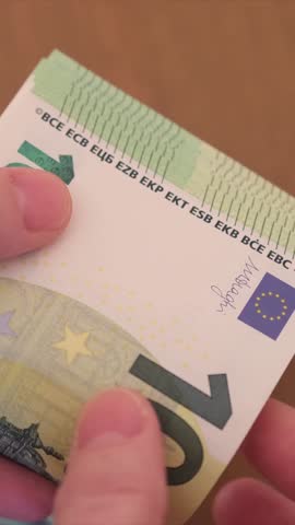 Two hands of a person with a stack of one hundred euro bills. Person counts cash.