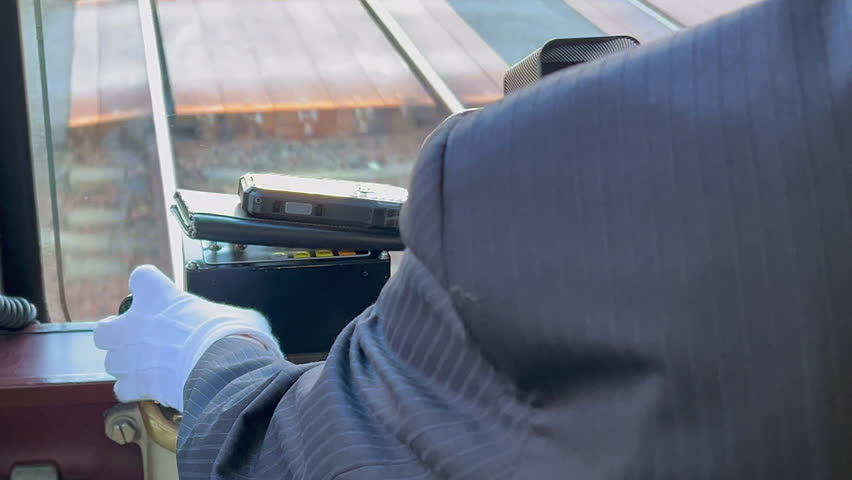 White glove tram conductor drives train on railroad tracks, detail view