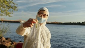 Young environmental inspector in hazmat suit collecting water samples from a polluted river, analyzing for contamination and monitoring ecological health under a clear sky - Powered by Shutterstock - Get 15% off with code: PIKWIZARD15