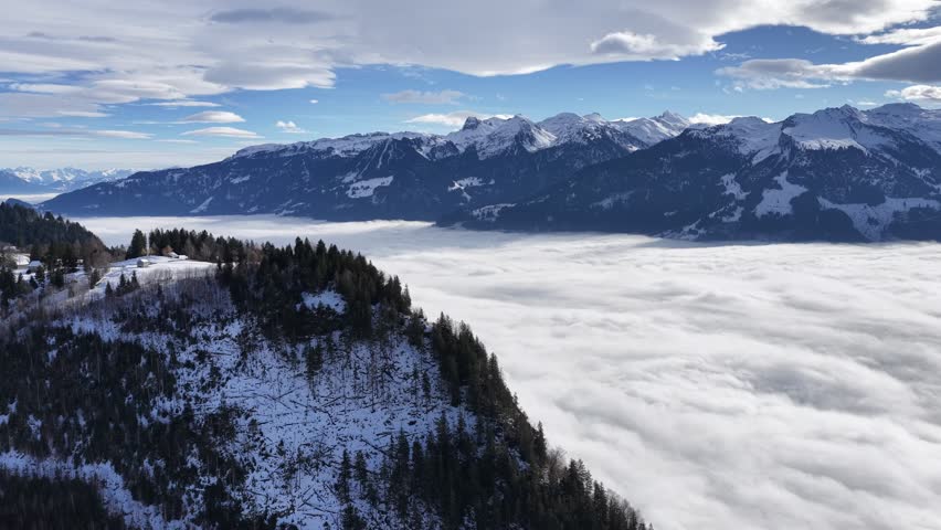 Churfirsten mountains, Walensee, Amden, Switzerland aerial drone shot above cloud inversion and snowy forest ridges, alpine winter nature and calm atmosphere.