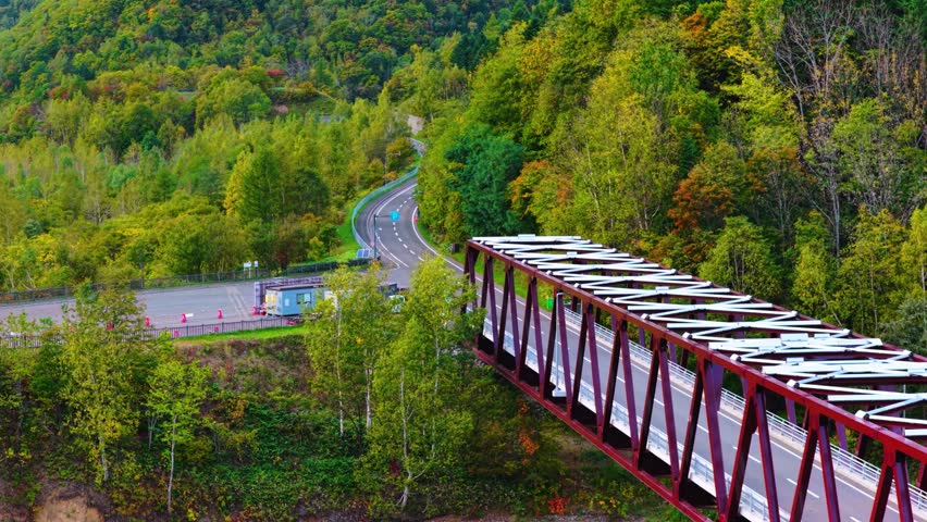 Mountain Road in Hokkaido Japan, Aerial View as Car Crosses Bridge at Dam