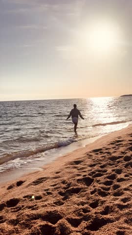 Woman Walking Along Shoreline With Wet Feet at Sunset Vertical Video