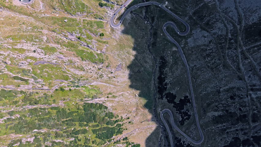 Scenic aerial view of winding Transfagarasan road in sunlight and shadow