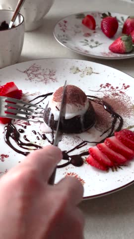 Person cook chocolate fondant, cake with melted chocolate, ice cream, and fruit. Making dessert at home.