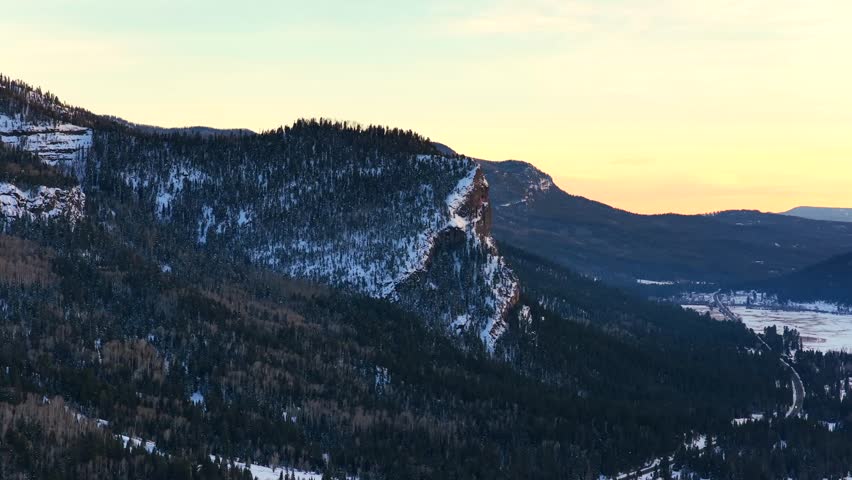 Close-up of the sheer rock face of Treasure Mountain near Wolf Creek Pass. The rugged cliffs feature deep crags and snow-dusted pine trees, showcasing the dramatic geology of the San Juan Mountains.