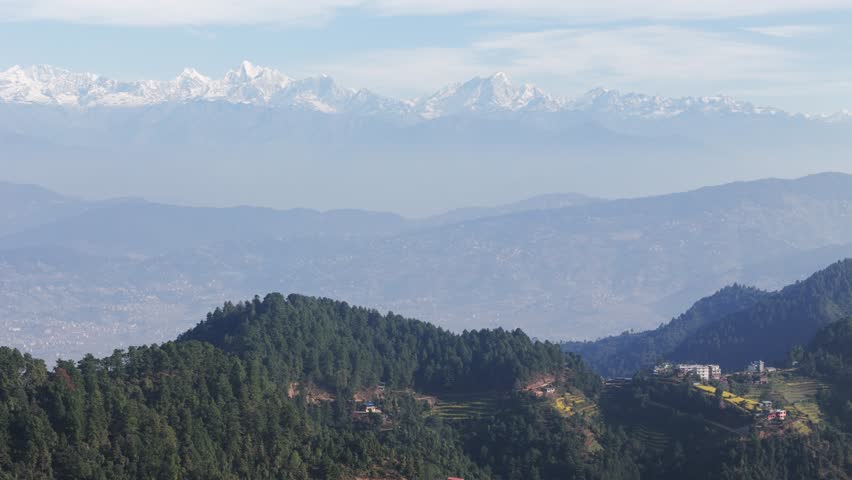 Experience Kathmandu Valley framed by the Himalayan mountain range. Drone footage captures the contrast of urban landscapes, lush green hills, and snow-capped peaks.