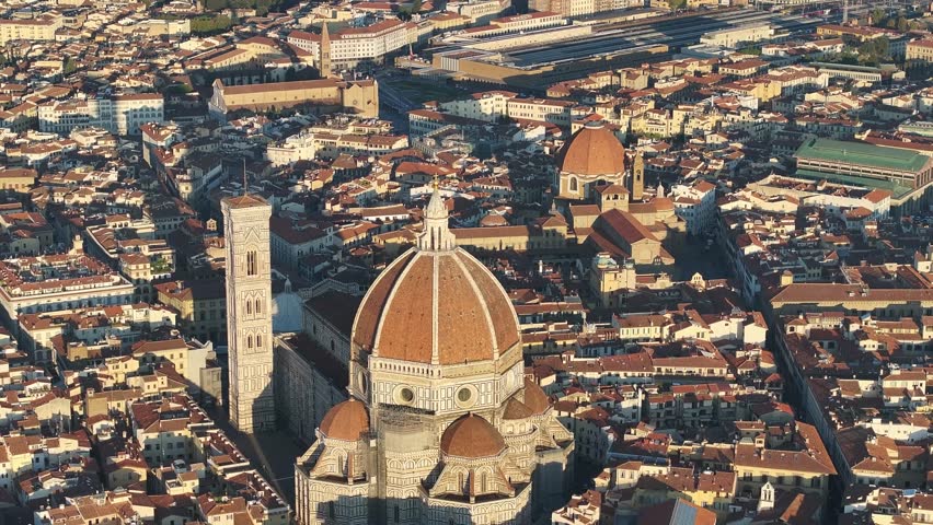 Stunning high aerial view from a drone showing the famous Florence Duomo, Campanile, and surrounding city rooftops bathed in morning sunlight.