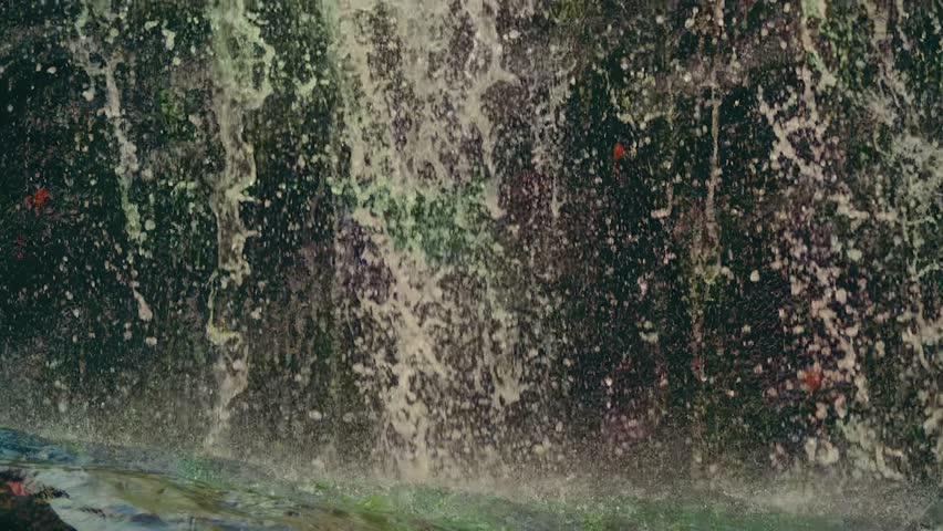 A close-up shot of a beautiful waterfall at Glendale Falls in Massachusetts. The clear water cascades down moss-covered rocks, creating a peaceful and refreshing natural scene.