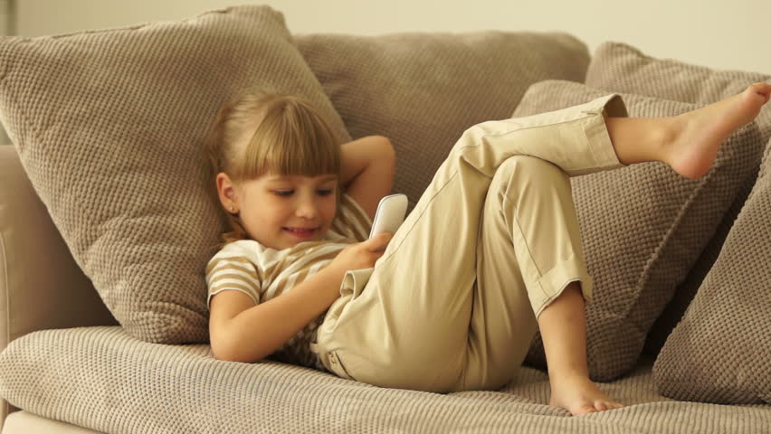 Little girl lying on sofa with phone
