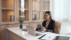 Asian businesswoman working in the office using a laptop and tablet for financial analysis. Successful female entrepreneur checking document and watching on monitor. - Powered by Shutterstock - Get 15% off with code: PIKWIZARD15