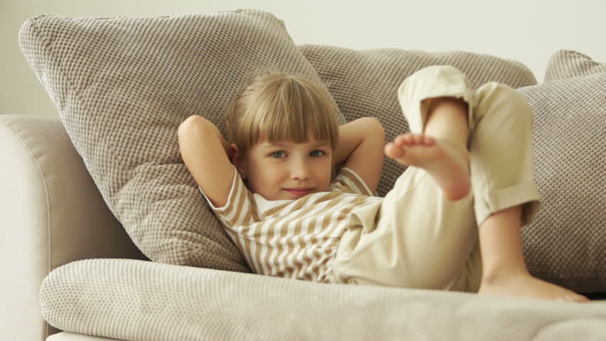 Little girl lying on sofa with ok hand sign
