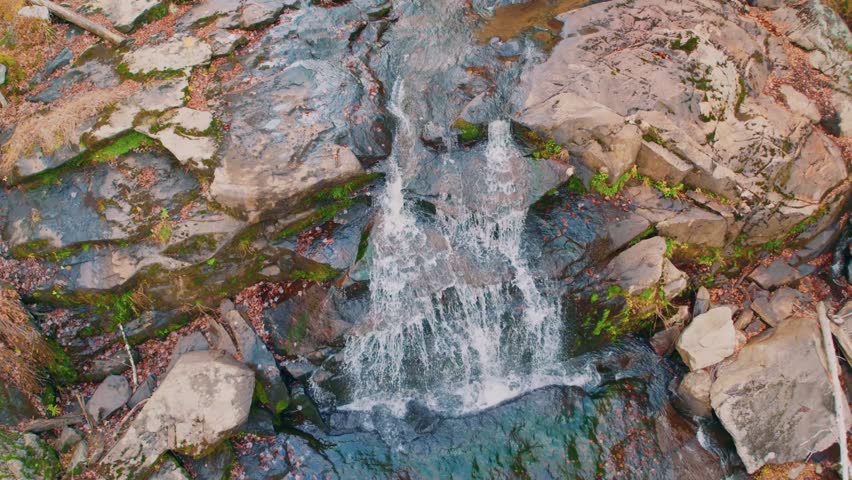 Footage of Glendale Falls, one of the longest waterfall runs in Massachusetts, located in a natural forest environment. The video captures water flowing rapidly over a series of dark, moss-covered roc