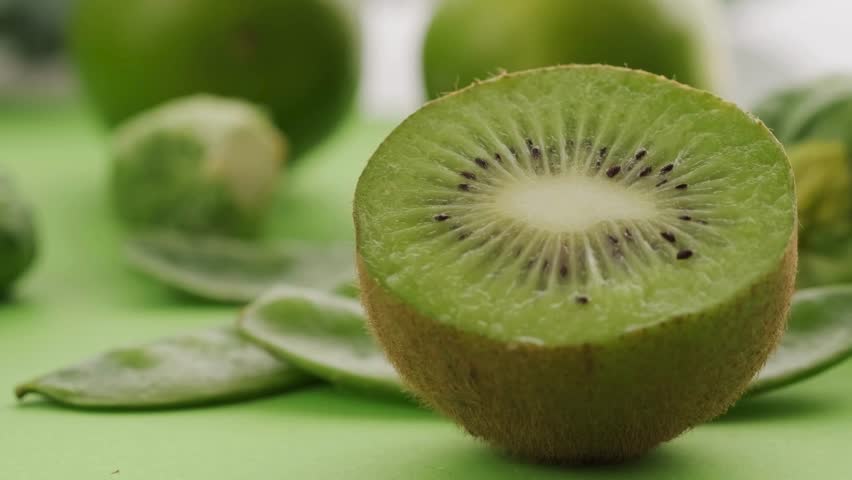 Close-up macro footage of fresh kiwi fruit sliced open to show bright green flesh and black seeds. The juicy texture and natural freshness make this video ideal for health food, vitamin C, organic produce, vegan and vegetarian diet, smoothie ingredients, nutrition, and clean eating concepts. Perfect for food advertising, wellness content, social media videos, cooking projects, and colorful fruit background use.