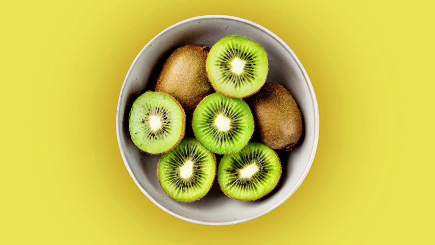 Close-up macro footage of fresh kiwi fruit sliced open to show bright green flesh and black seeds. The juicy texture and natural freshness make this video ideal for health food, vitamin C, organic produce, vegan and vegetarian diet, smoothie ingredients, nutrition, and clean eating concepts. Perfect for food advertising, wellness content, social media videos, cooking projects, and colorful fruit background use.