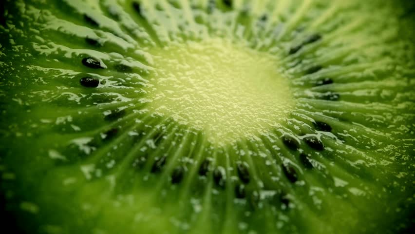 Close-up macro footage of fresh kiwi fruit sliced open to show bright green flesh and black seeds. The juicy texture and natural freshness make this video ideal for health food, vitamin C, organic produce, vegan and vegetarian diet, smoothie ingredients, nutrition, and clean eating concepts. Perfect for food advertising, wellness content, social media videos, cooking projects, and colorful fruit background use.