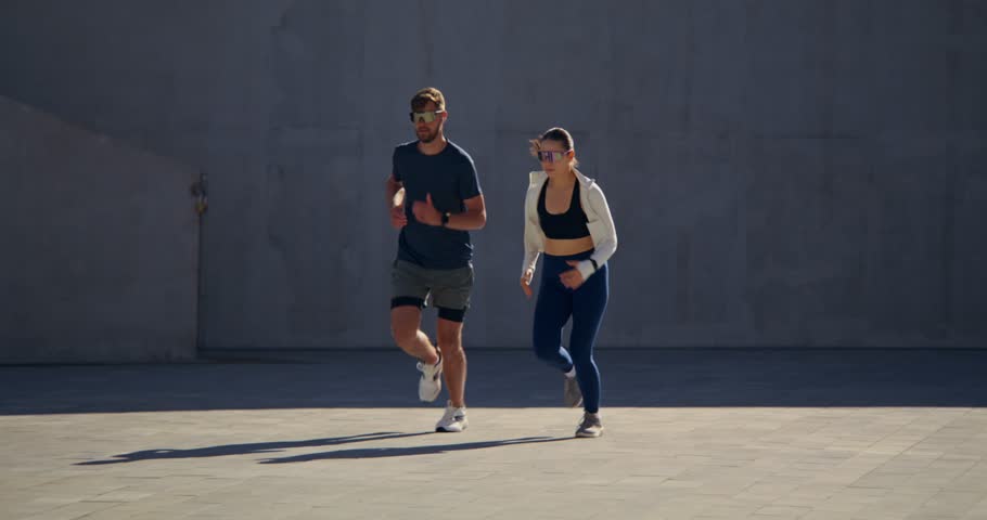 A young man and a woman are running along a city street. Joint training on a summer day