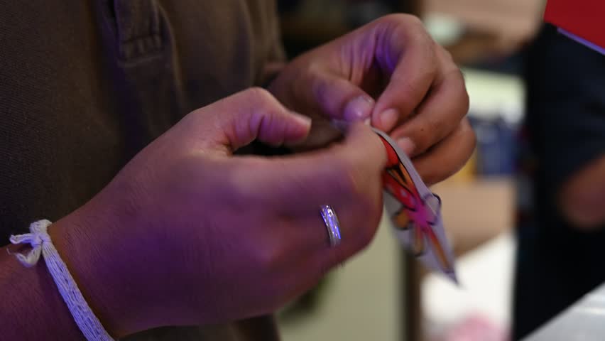 Bangkok, Thailand - 18th December 2025: Man manually printing alphabets on a pouch using an industrial printing machine, showcasing hands-on packaging, craftsmanship, manufacturing process, and small-scale production.