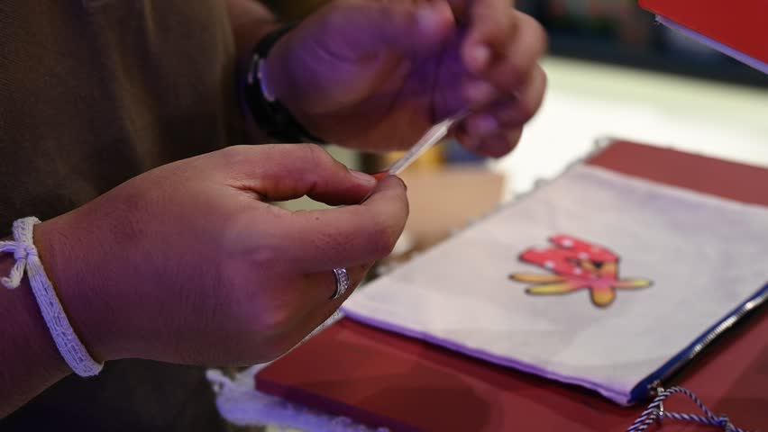 Bangkok, Thailand - 18th December 2025: Man manually printing alphabets on a pouch using an industrial printing machine, showcasing hands-on packaging, craftsmanship, manufacturing process, and small-scale production.
