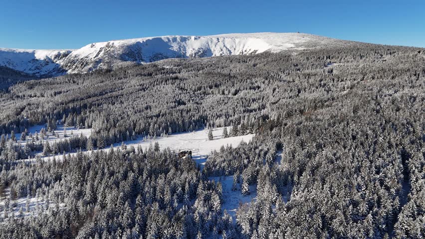 Aerial view of the Great Pond Cirque (Kocioł Wielkiego Stawu) in Karkonosze mountains with snow-covered slopes and winter forest.