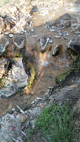 Hot spring water flows gracefully through rocky terrain, creating a serene and relaxing natural landscape.