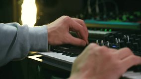 Close up view of musician hands playing a synthesizer, adjusting knobs and pressing keys during a studio recording session, composing electronic music with professional audio equipment - Powered by Shutterstock - Get 15% off with code: PIKWIZARD15