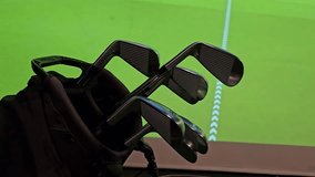 Golf clubs set up in indoor area with simulation background for practice session on a green course - Powered by Shutterstock - Get 15% off with code: PIKWIZARD15