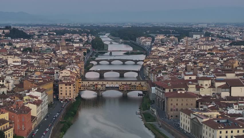 Historic city of Florence, Tuscany, Italy at dusk. The view is centered on the Ponte Vecchio, flowing into the Arno River and other bridges
