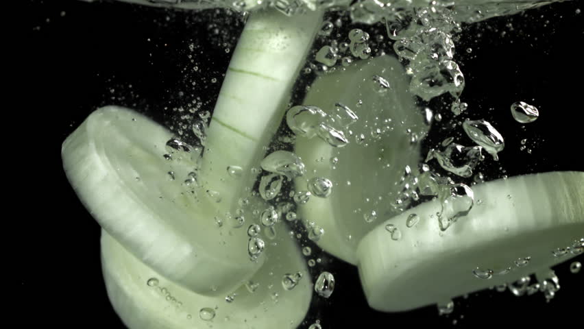 Sliced onion falling into water on black background. Filmed on a high-speed camera at 1000 fps. High quality FullHD footage