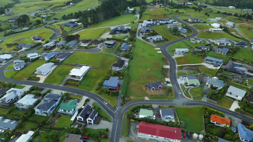 Coopers Bay Neighborhood with single family houses and green grass in garden on cloudy day. New Zealand in autumn. Aerial top down shot.