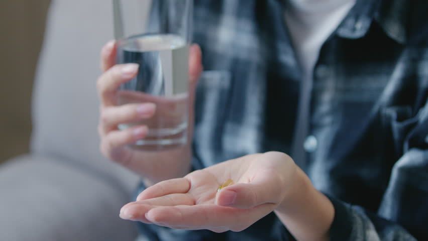 Unrecognizable young woman holding painkiller pills capsule in hand sick female taking medicine health care treatment vitamin supplement pharmacy therapy illness recovery wellbeing pregnancy wellness