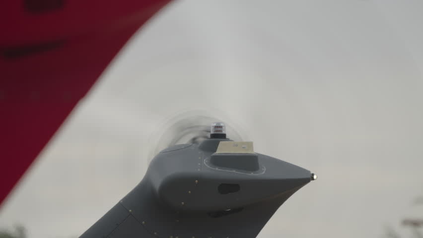 Close up of helicopter tail section with spinning rotor blades and visible motion blur against neutral background