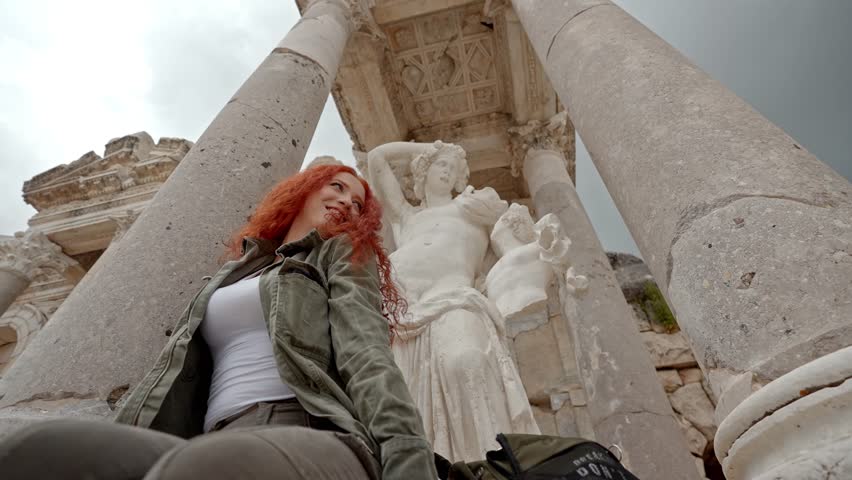 A visitor sitting and enjoying the atmosphere at the Roman fountain of Sagalassos Ancient City in Burdur, Turkey. Ancient columns, calm water, history, and cultural heritage create a peaceful scene.